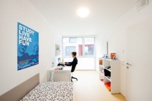 Student sitzt in seinem Zimmer vor dem Laptop