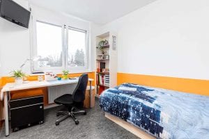 Blick in das Einzelzimmer mit Schreibtisch und Bett